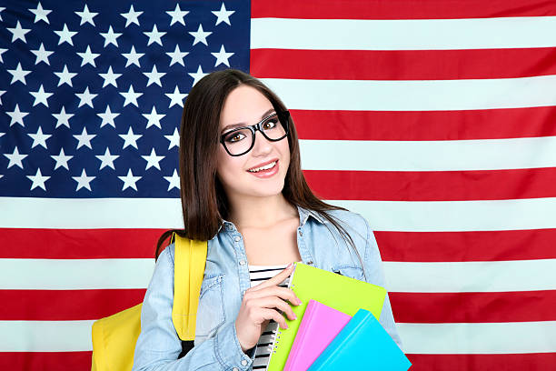 istock Young student with backpack and books on American flag background 2210440589