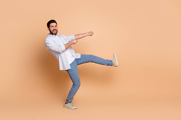 istock Smiling young man in casual attire posing energetically on beige background 2210441039