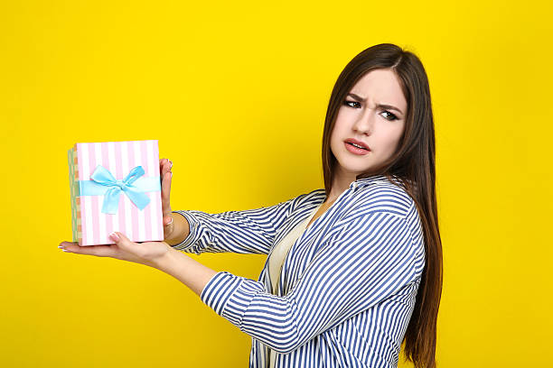 istock Beautiful young woman with gift box on yellow background 2210441782