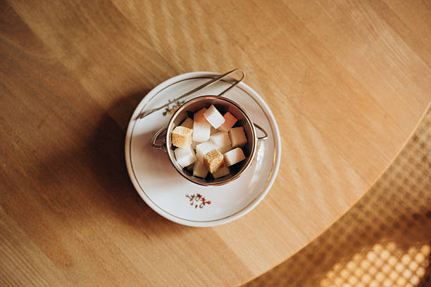 Brown and white sugar cubes in ceramic bowl on wooden table. Top view. Copy space. Vintage stye. Creative layout. Food and healthy eating concept.