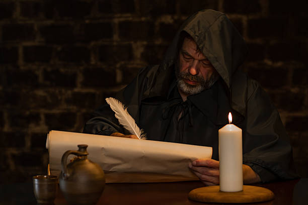 istock A medieval monk writes with a quill pen on parchment by candlelight. 2210455456