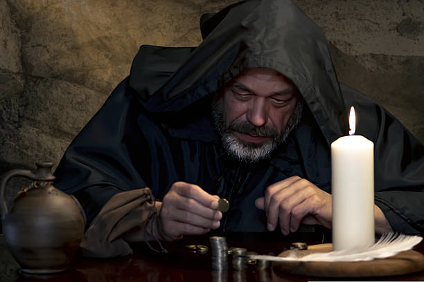 istock A medieval monk counting coins by candlelight. 2210455531