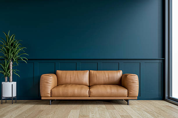 istock Modern interior: a living room with a brown leather sofa, half dark blue wainscoting and half dark blue plaster wall background and decoration 2210460056