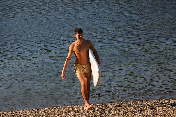 Young man with surfboard walking on the beach