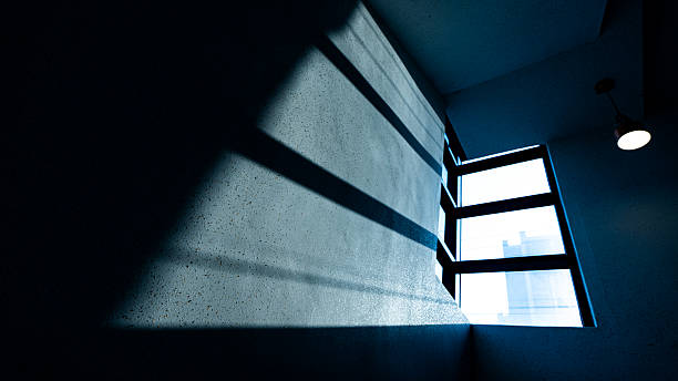 Light striking the cement wall of a South Korean stairwell with apartment complex off in the hazy distance.