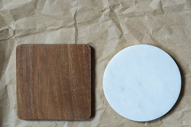 istock empty small square cutting board from acacia wood and rounded marble pad on crumpled craft paper. Clean paper background. Horizontal empty paper template for posters and banners. 2210464481