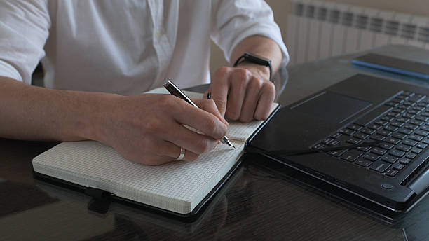 istock Focused Professional Writing Notes in Office With a Laptop on the Desk 2210465154
