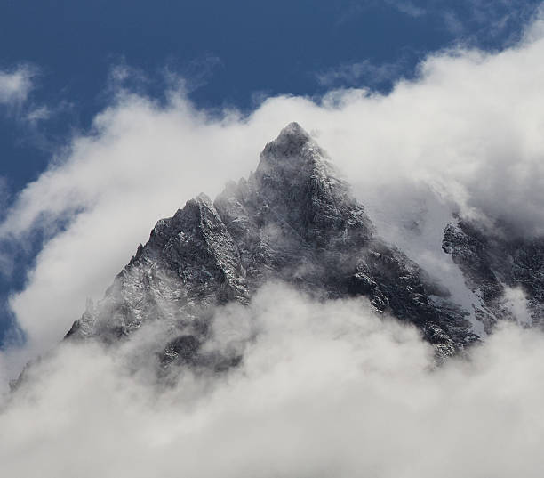 istock Majestic Mountain Peaks Shrouded by Clouds Under a Clear Blue Sky 2210471100