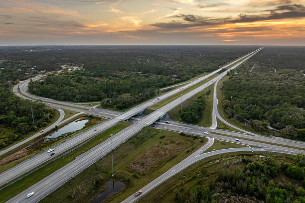 istock Elevated view of freeway exit junction over road lanes with fast moving traffic cars and trucks at sunrise. Interstate transportation infrastructure in USA 2210472010