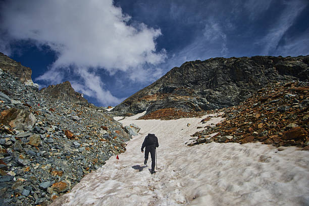 Individual trekking on a snow-covered hill wearing a lime green jacket. Adventurer exploring a winter wonderland. Solitary figure in a pristine snowy environment.
