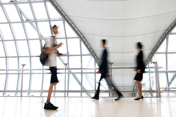istock A people walking in motion blur on white corridor with large windows. Blurred people walking in a modern building. Abstract image of people in the lobby. 2210477503