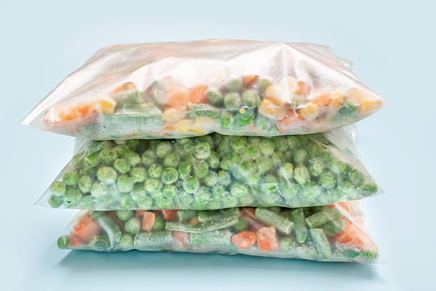 istock Stack of bags with frozen vegetables on blue background close-up. 2210482058