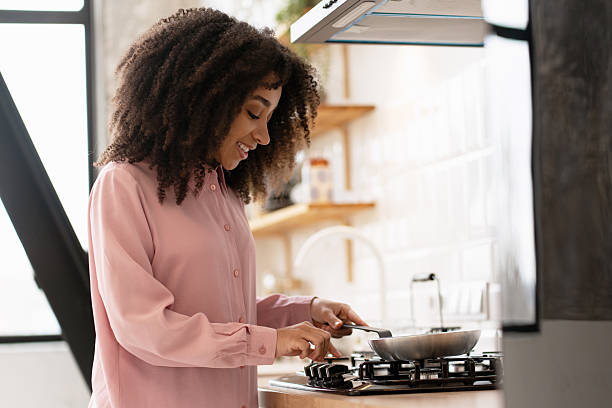 istock Young woman cooking with pan on stove in modern kitchen 2210495083
