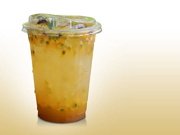 Passion Fruit Soda in a clear plastic glass. Decorated with flowers and leaves on gradient yellow and white background, fruit, nature, drink, fresh, copy space