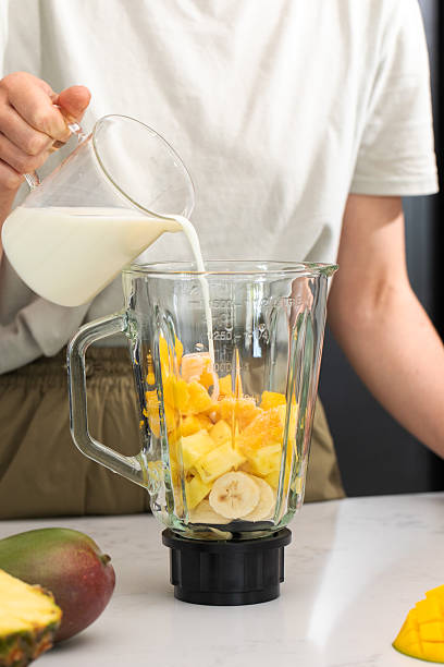 istock Fresh tropical smoothie preparation with mango, pineapple and milk in a modern kitchen 2210496725