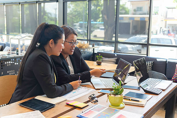 istock Two happy busy female employees working together using computer planning project. 2210499374