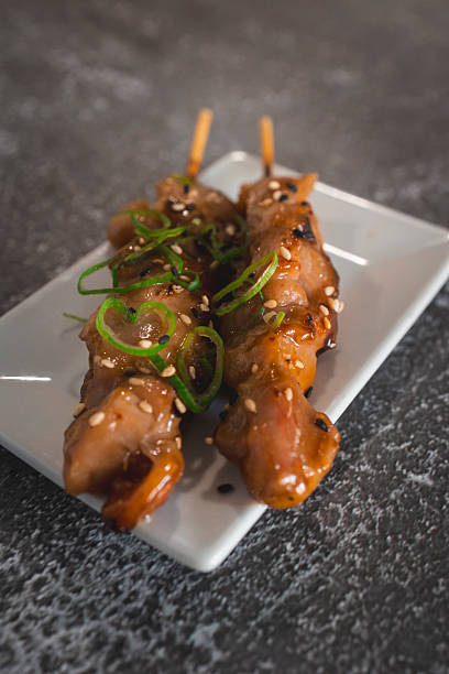 istock Two chicken yakitori skewers resting on a white plate 2210500307