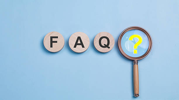 faq、よくある質問の概念。木製のfaqタイル3枚と黄色のクエスチョンマークが付いた虫眼鏡。寄せられた質問と回答。インターネットサイト上の指示とルール。 - よくある質問 ストックフォトと画像