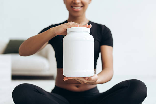 istock Smiling sportswoman showing nutritional supplement container after training 2210502048