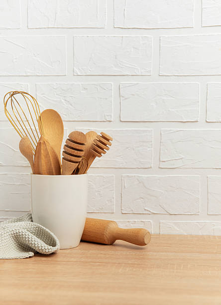 Kitchen utensils resting on wooden countertop by white brick wall