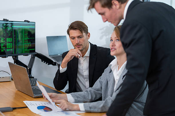 istock Business professionals discussing data analysis in a modern office environment with charts and computers in view 2210507161