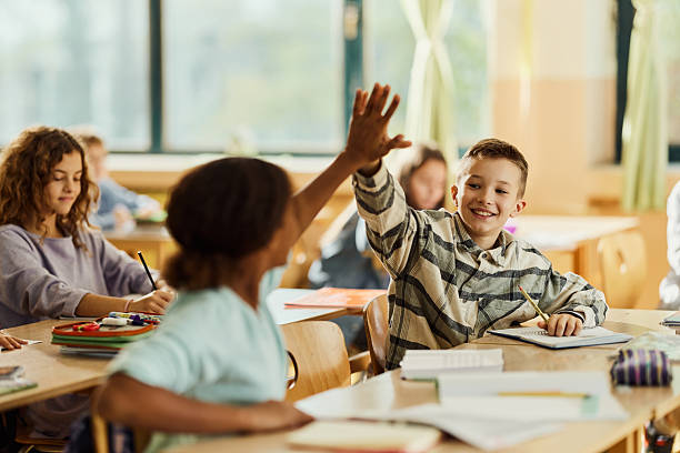 istock Happy students giving each other high-five on a class at school. 2210507176