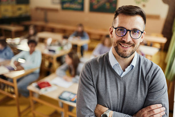 istock Happy elementary teacher in front of his students in the classroom. 2210507660
