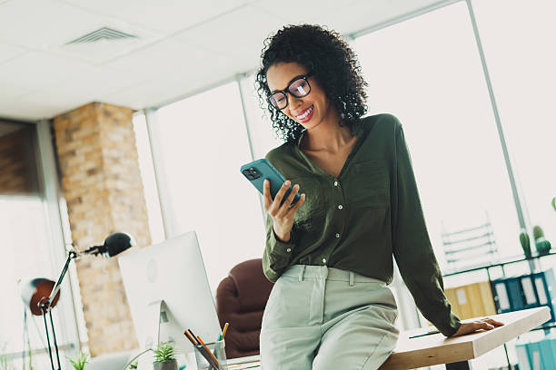 istock Confident young businesswoman checking her smartphone while working in a bright modern office environment 2210507820