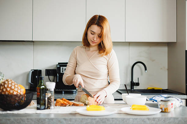 istock Woman Slicing Fresh Bread at Kitchen Counter 2210515055