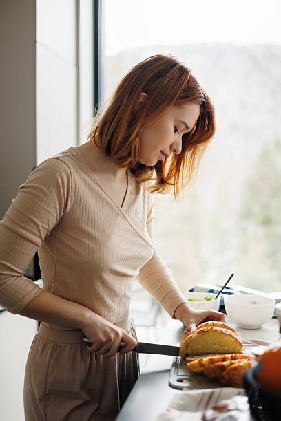 istock Woman Slicing Fresh Bread at Kitchen Counter 2210515158