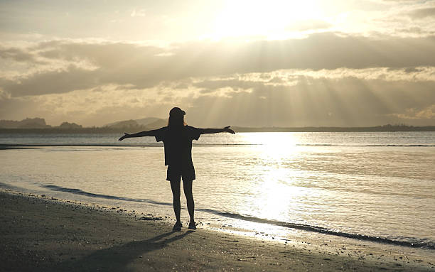 istock Silhouette of a woman open arms while strolling on the beach 2210515461