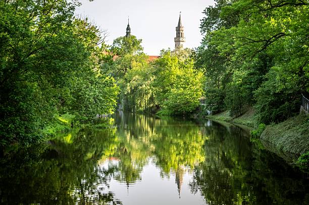 istock Lush park with river and church tower reflection. 2210516394