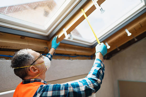 istock Professional construction worker wearing safety gear measures roof window frame in bright attic 2210518469