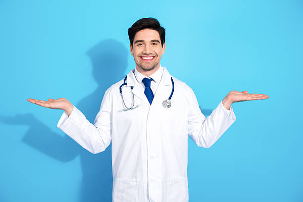 istock Young doctor in a white uniform smiling confidently against a blue background, emphasizing professionalism and healthcare concepts 2210518570