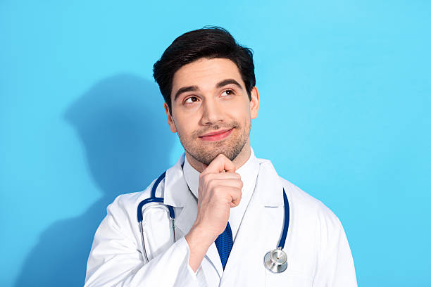 istock Medical professional thinking about healthcare solutions while posing on a vibrant blue background wearing a white lab coat 2210518669