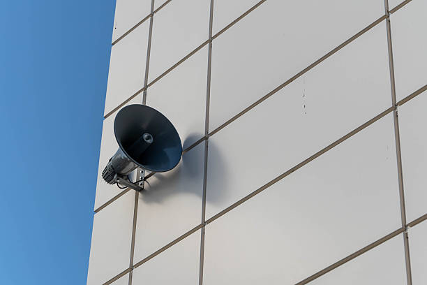 istock Loudspeaker announcing on white building with blue sky background 2210520190