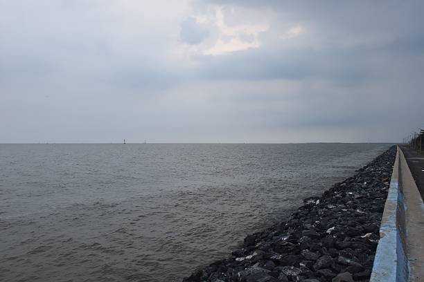Panoramic of a dyke next to the sea. Location is the Hondsbossche Zeeweering, a 6 km long dyke between Camperduin and Petten, Netherlands, separating the sea from the polder and wetlands  below sea level.