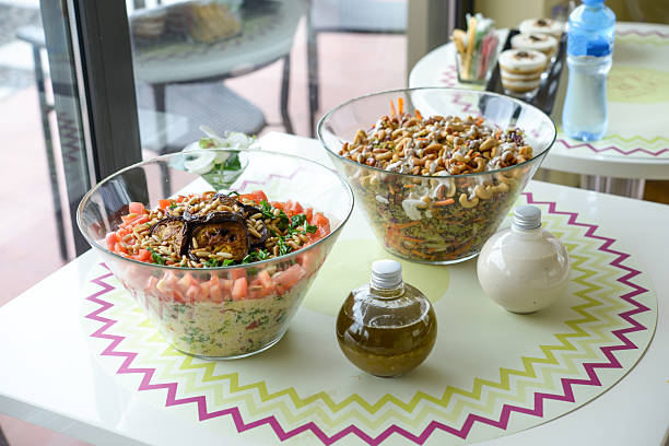 Assorted Salads in Glass Bowls include grains, vegetables, tomato and nuts served on a table with dressing bottles side view