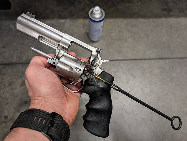 istock A man's hand holds a silver revolver with the cylinder open during the gun cleaning process using a cleaning rod. 2210524442
