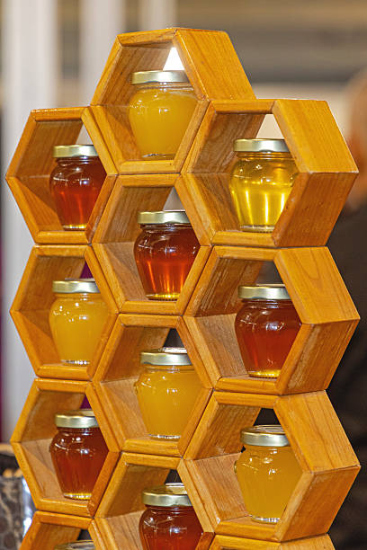 Natural Bee Honey in Small Glass Jars at Wooden Rack Display