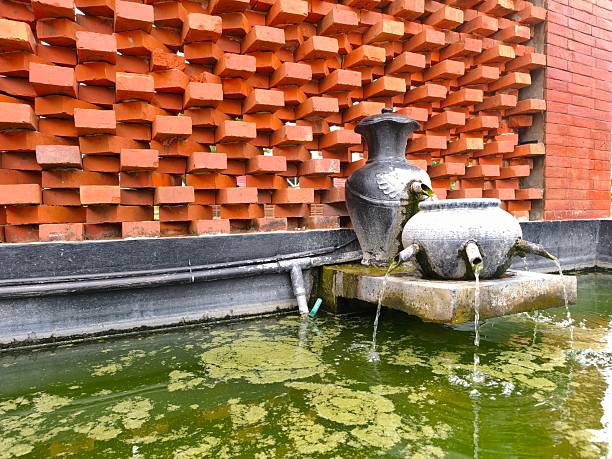 a fountain in a mossy and unkempt fish pond