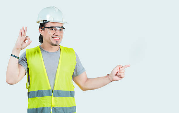 istock Latin young engineer recommending and pointing side isolated. Cheerful and friendly engineer pointing at promotion isolated 2210527244