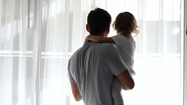 istock Father and daughter sharing a tender moment at hotel window 2210527935