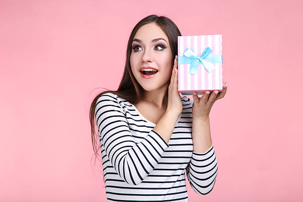 istock Beautiful young woman with gift box on pink background 2210529121
