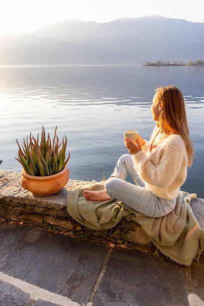istock Woman Relaxing with Coffee by Scenic Lakeside 2210529746