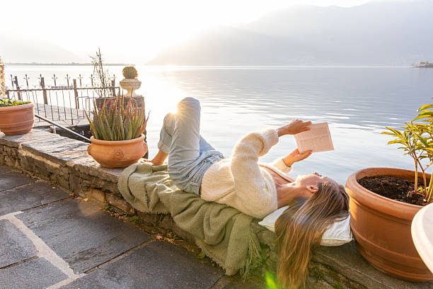 istock Woman Relaxing with a Book by the Waterfront at Sunset 2210529779