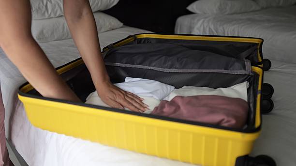 istock Woman packing clothes in yellow suitcase on bed 2210530059