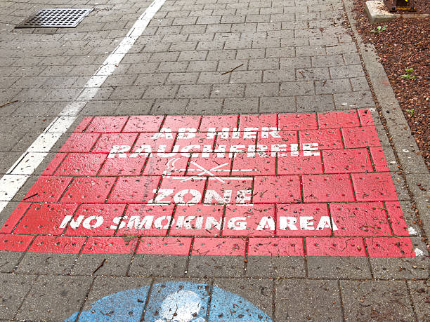 istock Outdoor red brick no smoking area sign on sidewalk in multiple languages 2210530787