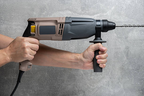 istock Large image of mans hand holding an electric perforator, against background concrete wall. 2210534773
