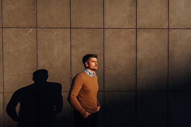 istock Pensive businessman standing near wall with long shadow looking away 2210535284